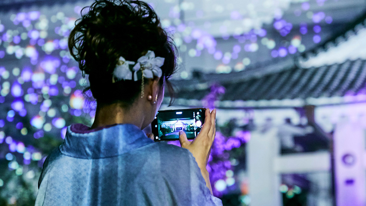プロジェクションマッピングをスマートフォンで撮影する参拝者
