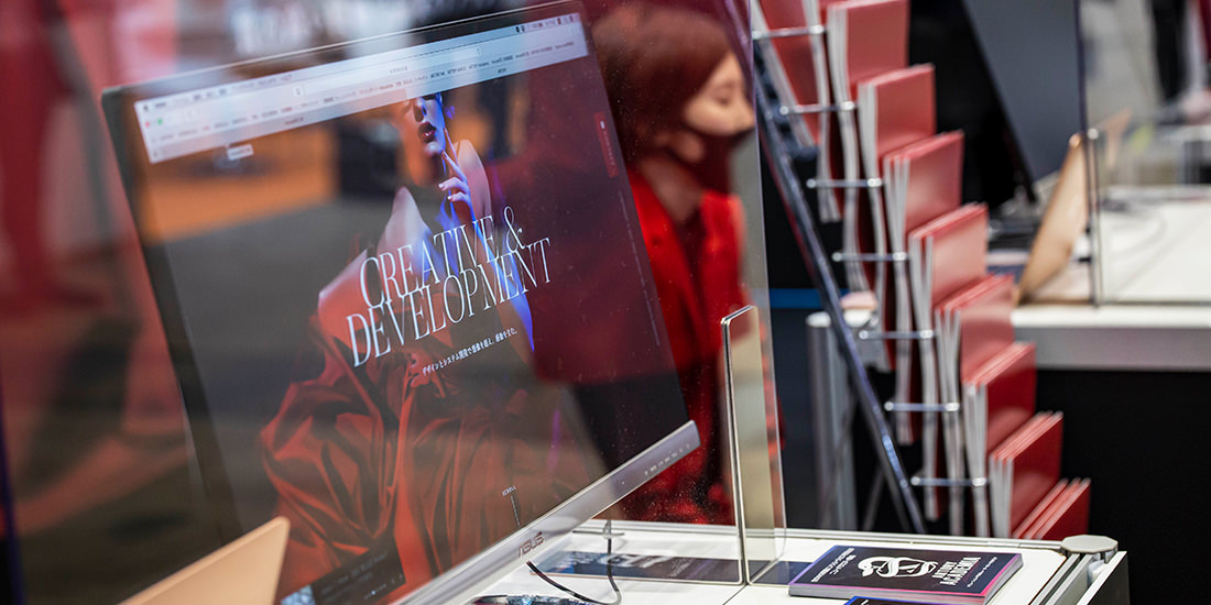 感染対策のため、アクリル板越しに商談するスタッフ