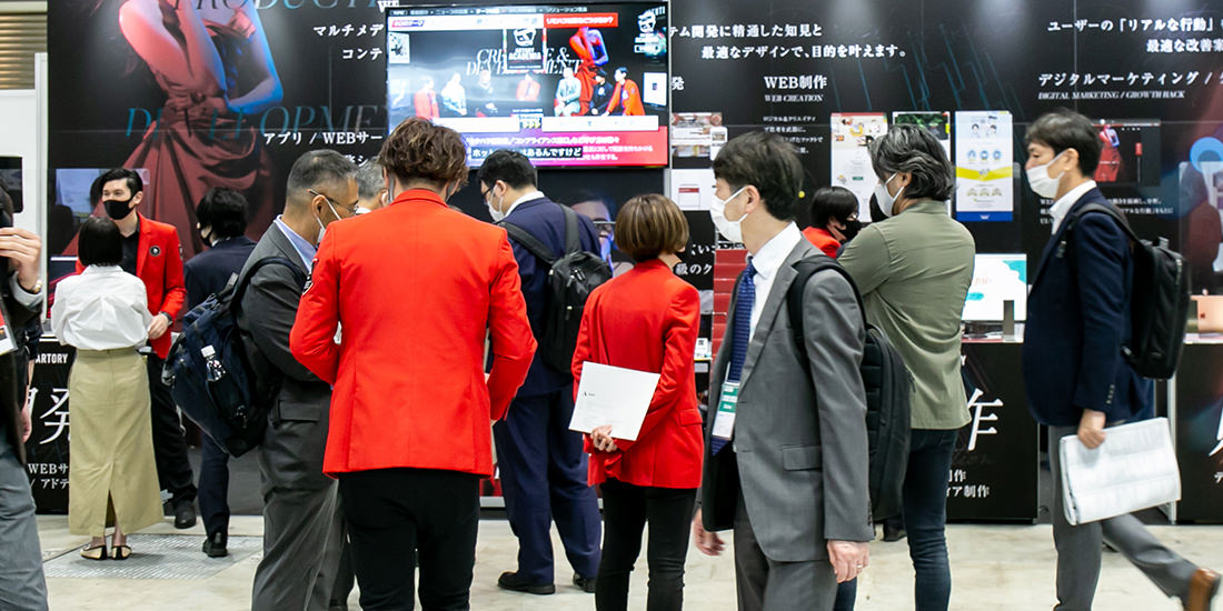 展示会ブースにて赤いジャケットを着たアートリーのスタッフが来場者と話している